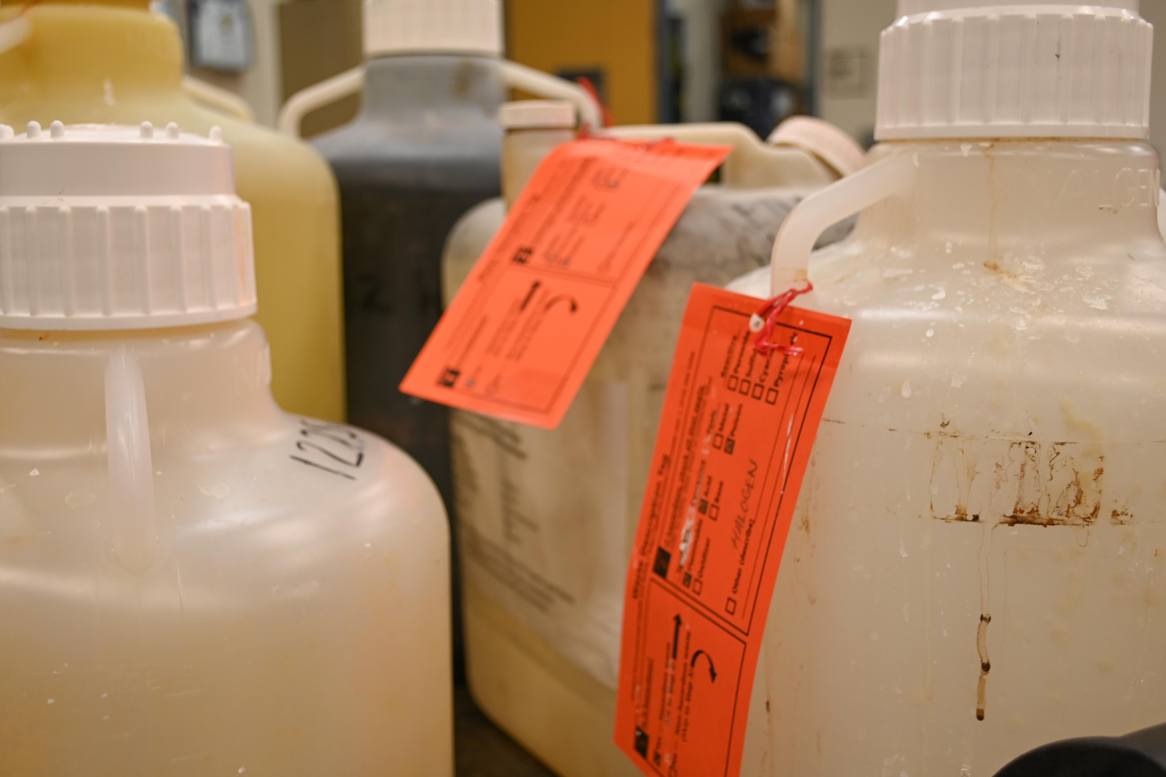 Example of orange hazardous waste tags on chemicals to be collected by EH&S