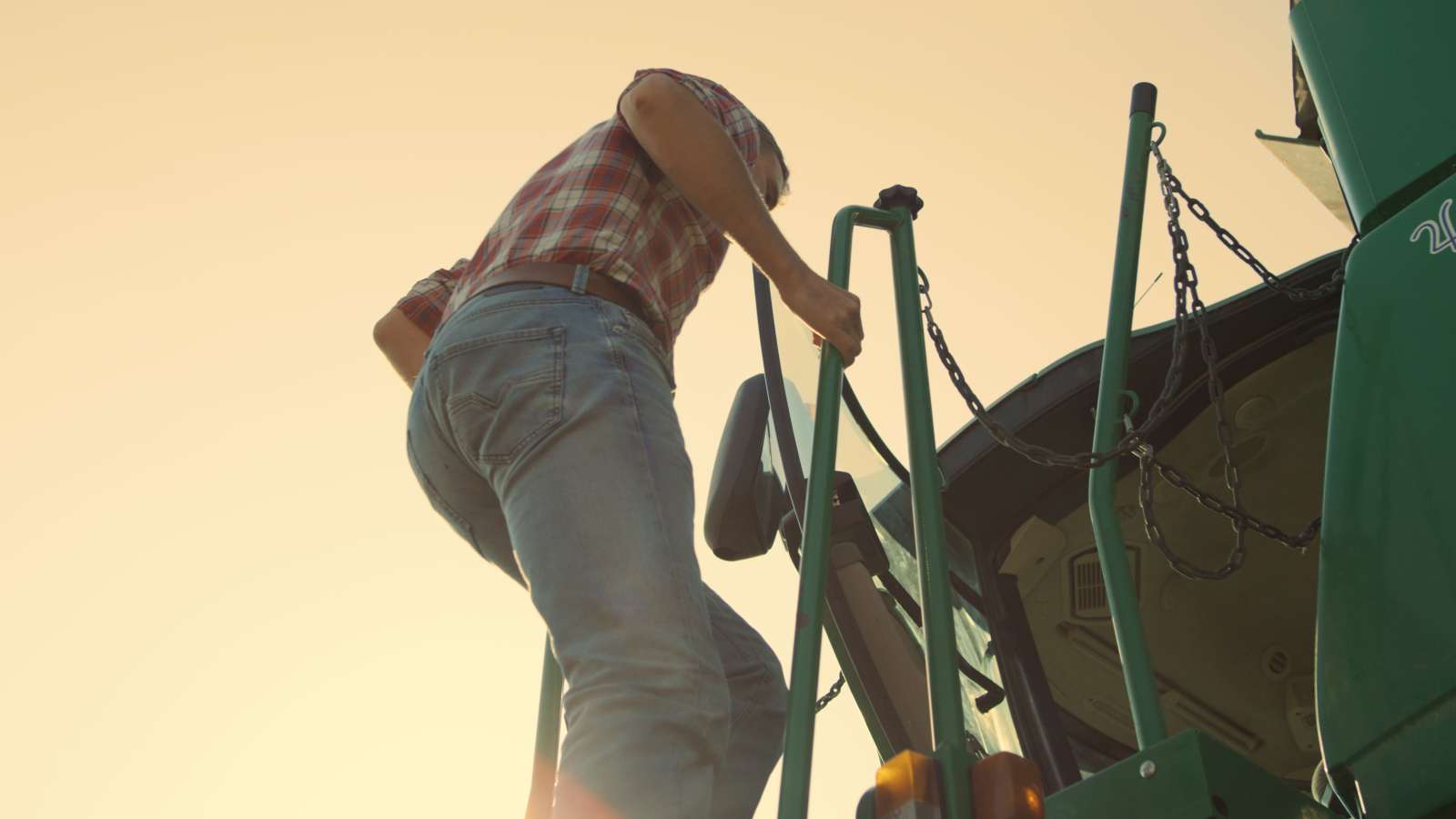 Photo of a person climbing up the ladder to the cab of a tractor