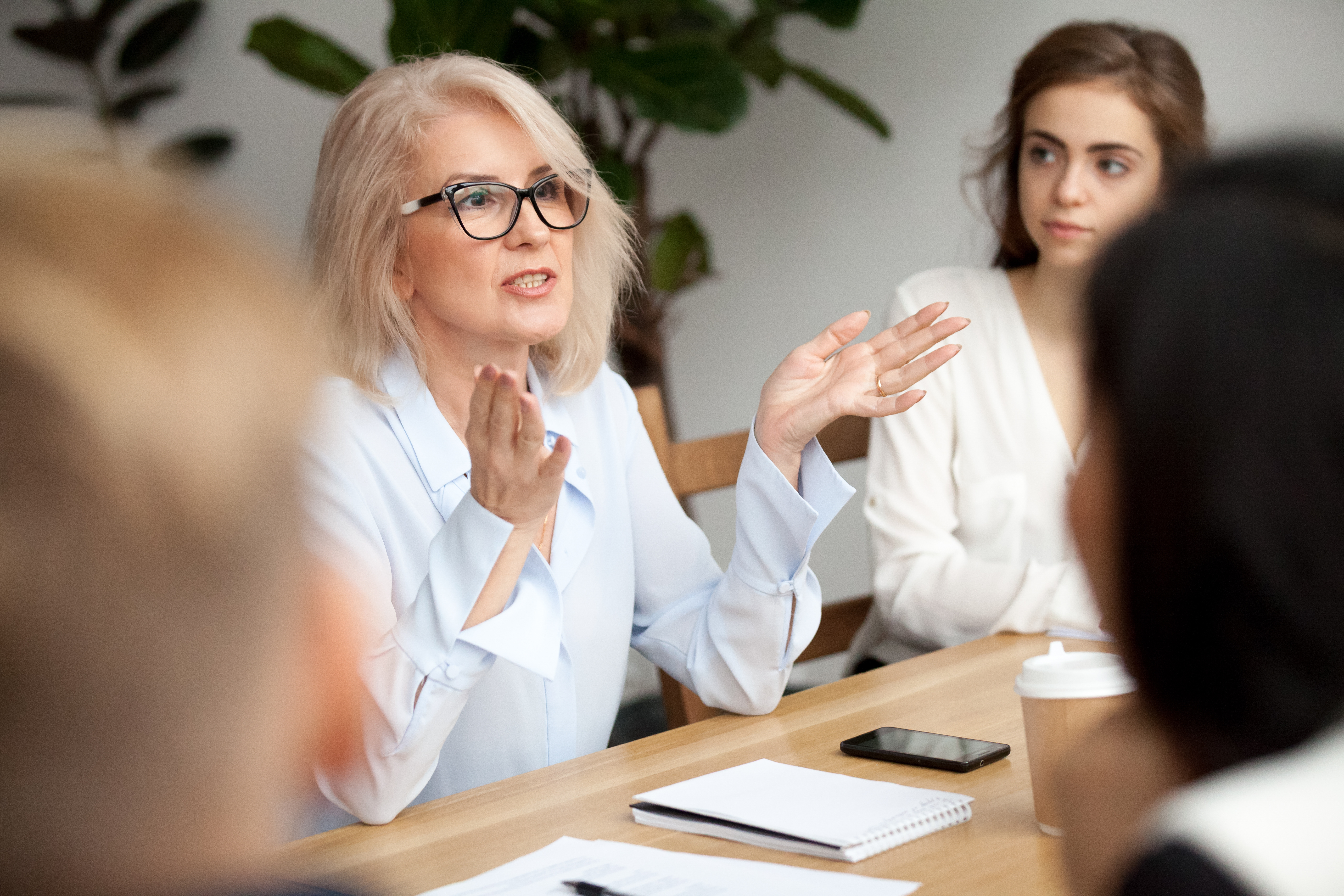 Group of people sitting at a conference table focused on one person speaking in the center