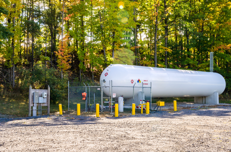 White aboveground storage tank next to trees