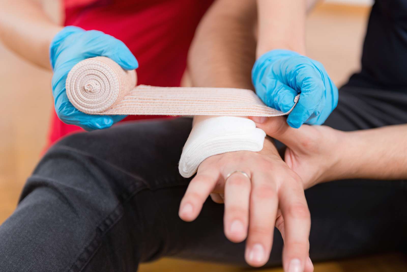 A first responder wraps a bandage around another person's injured hand