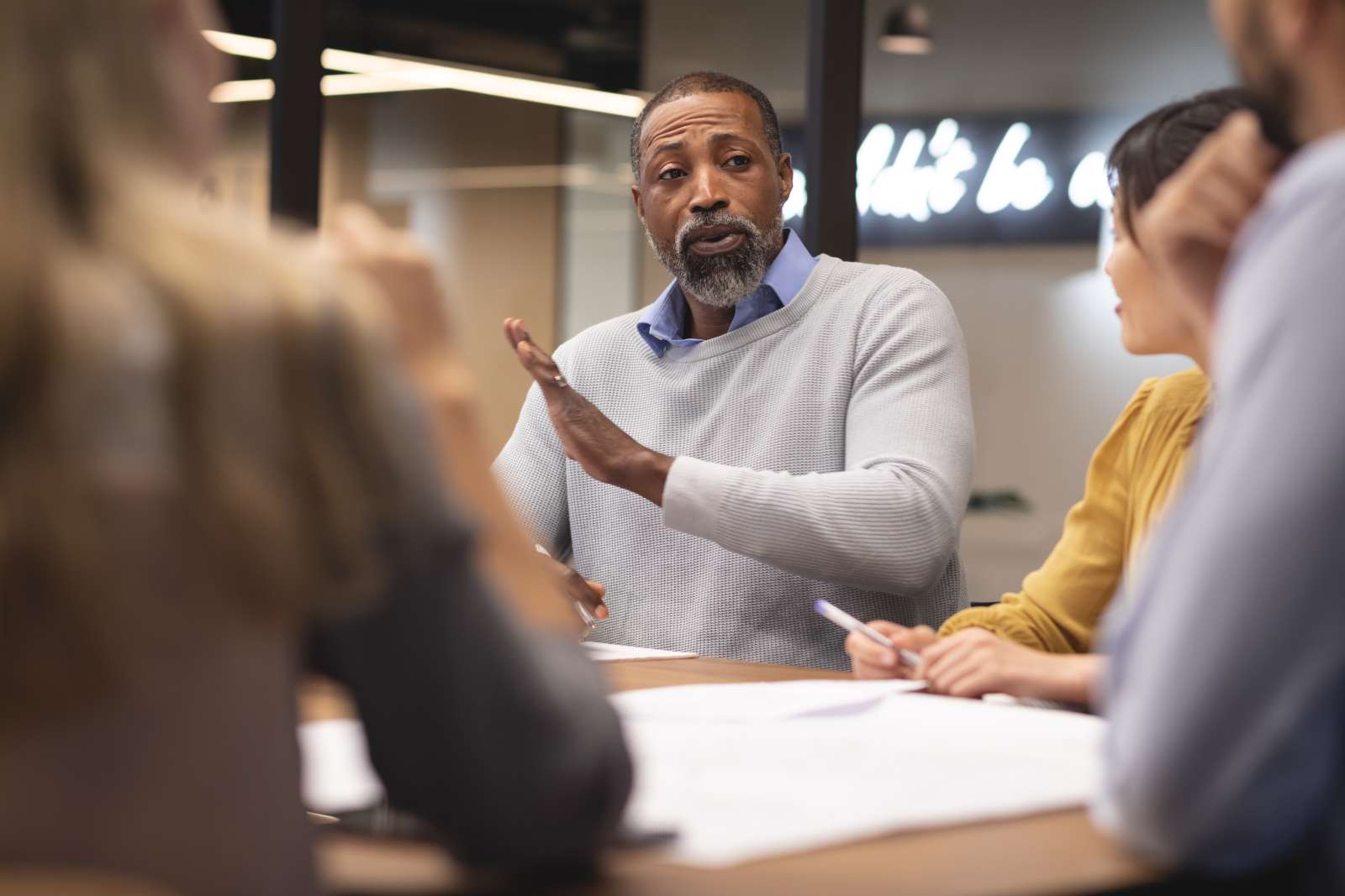 Four people sitting at a table. One person is talking while the others listen attentively.