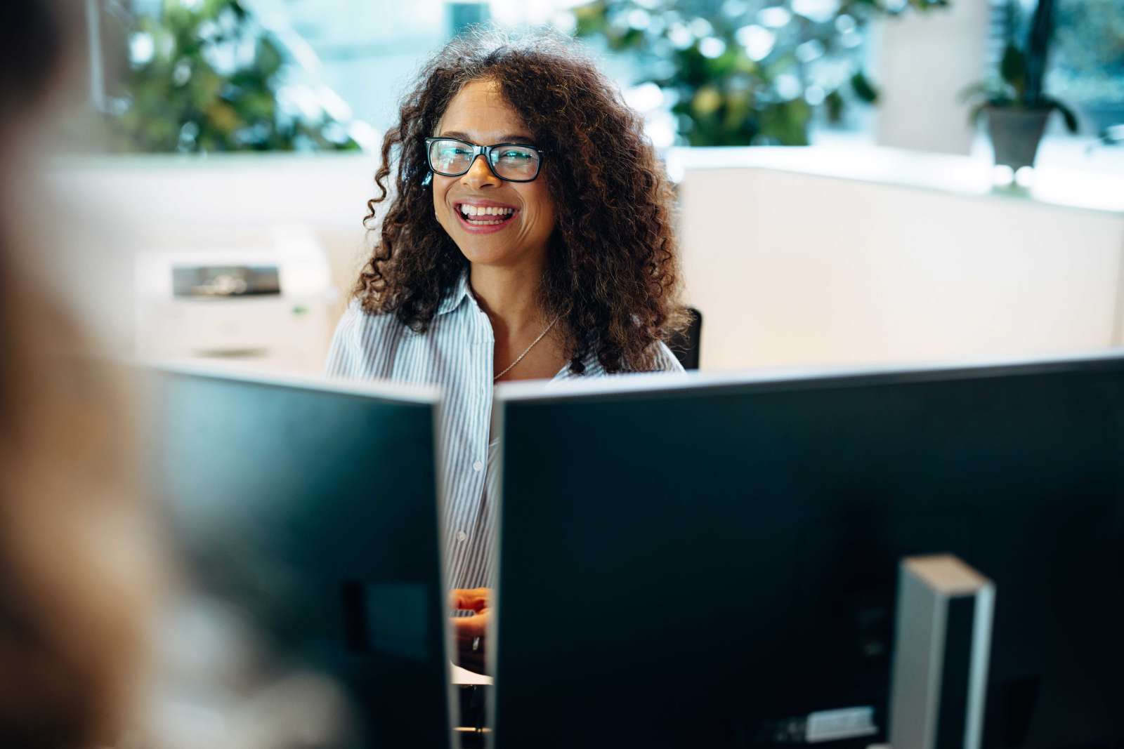 Person sitting at desk with two monitors smiles